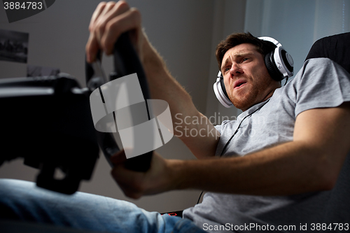 Image of man playing car racing video game at home