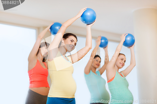 Image of happy pregnant women exercising with ball in gym