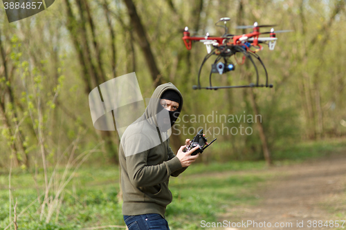 Image of Man in mask operating a drone with remote control.