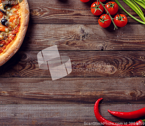 Image of Italian pizza with tomatoes on a wooden table, top view.