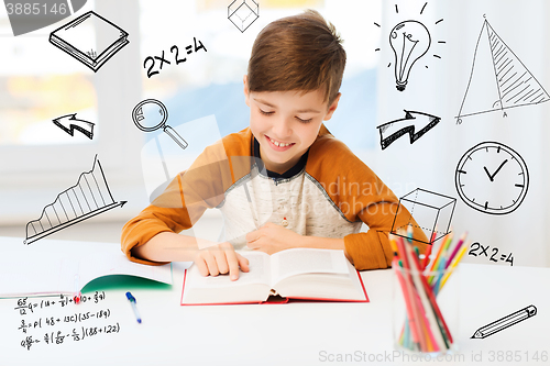 Image of smiling, student boy reading book at home