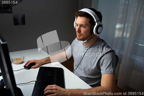 Image of man in headset playing computer video game at home