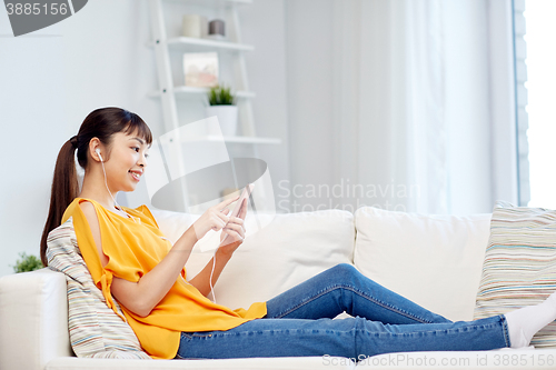 Image of happy asian woman with smartphone and earphones