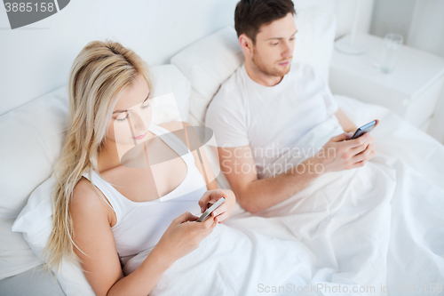 Image of couple with smartphones in bed