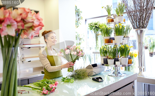 Image of smiling florist woman making bunch at flower shop