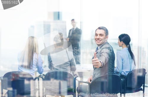 Image of businessman with team showing thumbs up in office