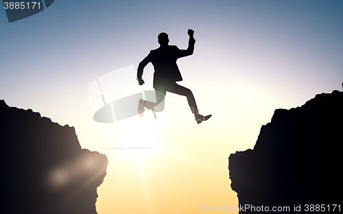 Image of happy businessman jumping between rocks