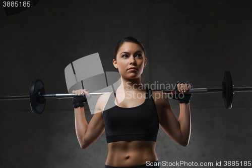 Image of young woman flexing muscles with barbell in gym