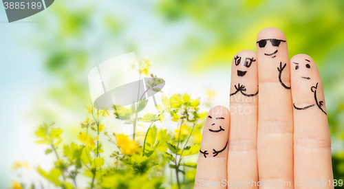Image of close up of fingers with smiley faces over nature