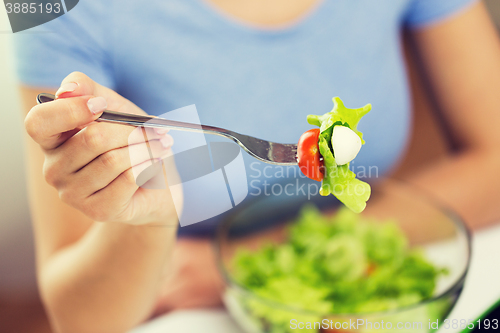 Image of close up of young woman eating salad at home