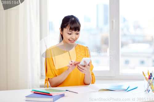 Image of happy young woman student with smartphone at home