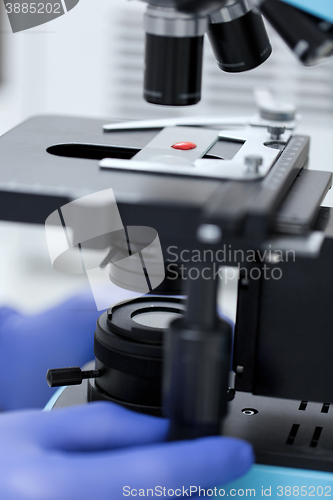 Image of close up of hands with microscope and blood sample