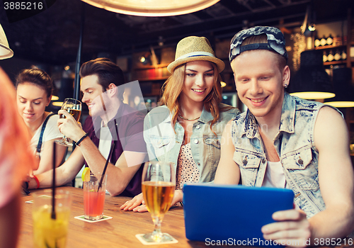Image of happy friends with tablet pc and drinks at bar