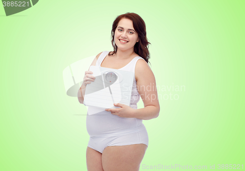 Image of happy young plus size woman holding scales