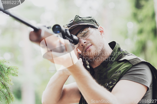 Image of young soldier or hunter with gun in forest