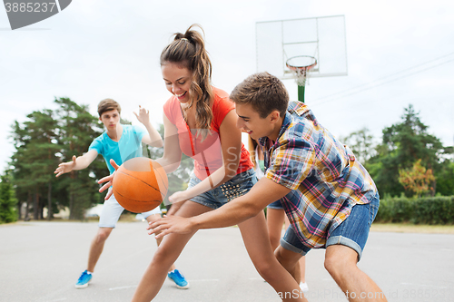 Image of group of happy teenagers playing basketball