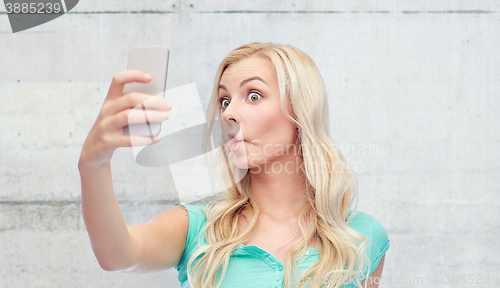 Image of funny young woman taking selfie with smartphone