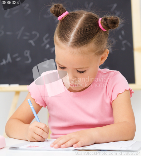 Image of Little girl is writing using a pen