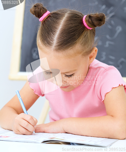 Image of Little girl is writing using a pen