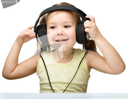 Image of Little girl is enjoying music using headphones