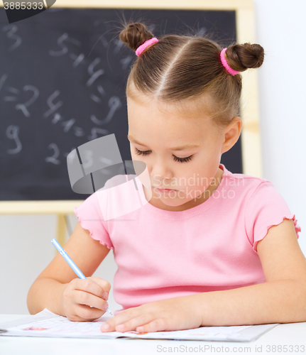 Image of Little girl is writing using a pen