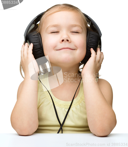 Image of Little girl is enjoying music using headphones