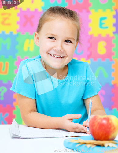 Image of Little girl is writing using a pen