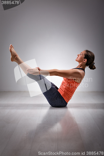 Image of Woman practices yoga asana Paripurna navasana