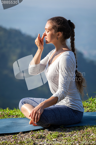 Image of Woman practices pranayama in lotus pose outdoors