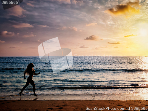 Image of Beautiful athletic woman running along sea beach in the morning