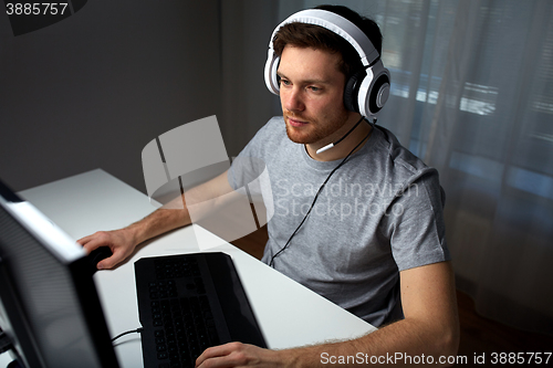 Image of man in headset playing computer video game at home