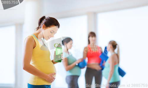 Image of happy pregnant woman with water bottle in gym
