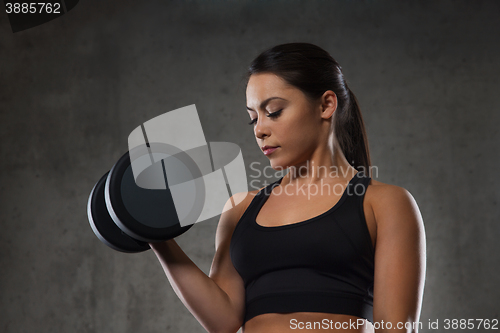 Image of young woman flexing muscles with dumbbells in gym