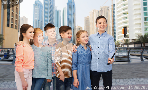Image of happy children with smartphone and selfie stick