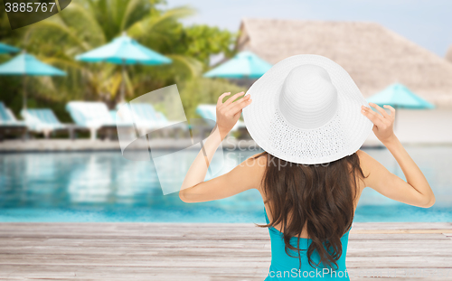 Image of woman in swimsuit and sun hat from back over beach