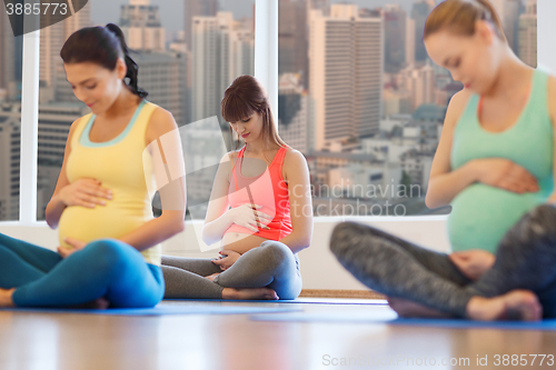 Image of happy pregnant women exercising yoga in gym