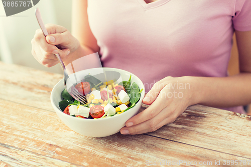 Image of close up of young woman eating salad at home