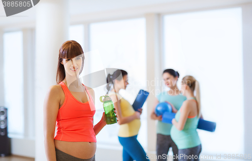 Image of happy pregnant woman with water bottle in gym