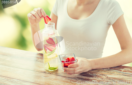 Image of close up of woman with fruit water in glass bottle