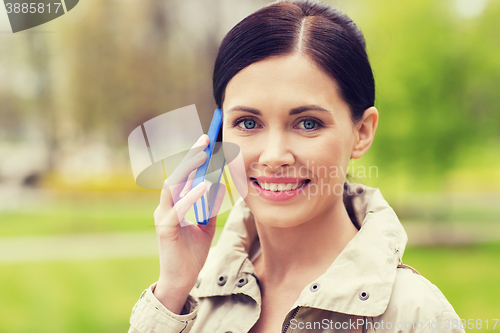 Image of smiling woman calling on smartphone in park