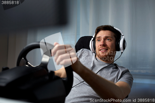 Image of man playing car racing video game at home