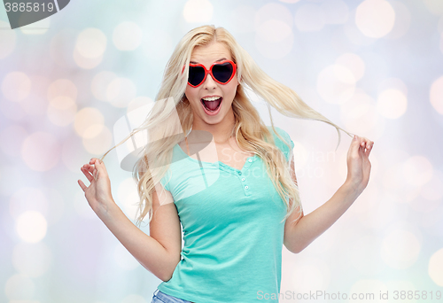 Image of happy young woman in heart shape sunglasses