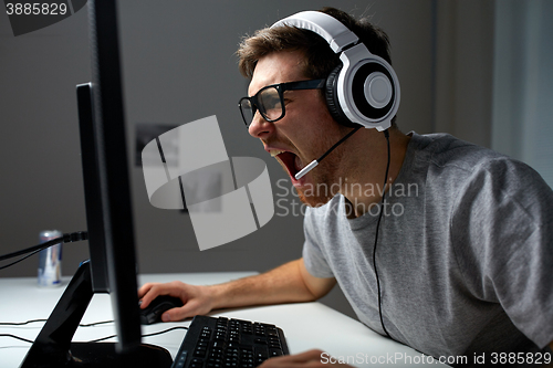 Image of man in headset playing computer video game at home