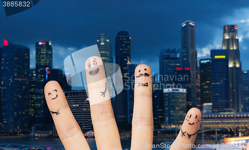 Image of close up of fingers with smiley faces over city