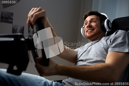 Image of man playing car racing video game at home