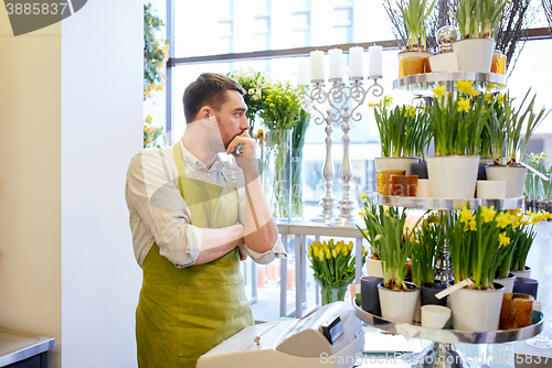 Image of sad florist man or seller at flower shop counter