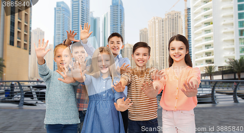 Image of group of happy children waving hands