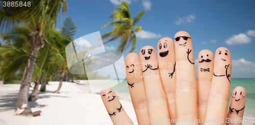 Image of close up of fingers with smiley faces on beach