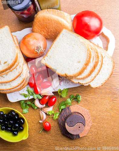 Image of top-view of a wood table with olives tomatoes bread