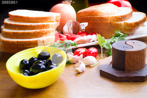 Image of top-view of a wood table with olives tomatoes bread